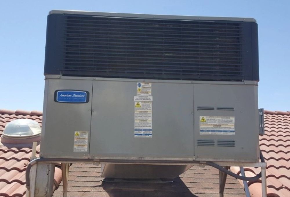 Rooftop air conditioning unit on a sloped tile roof with vents