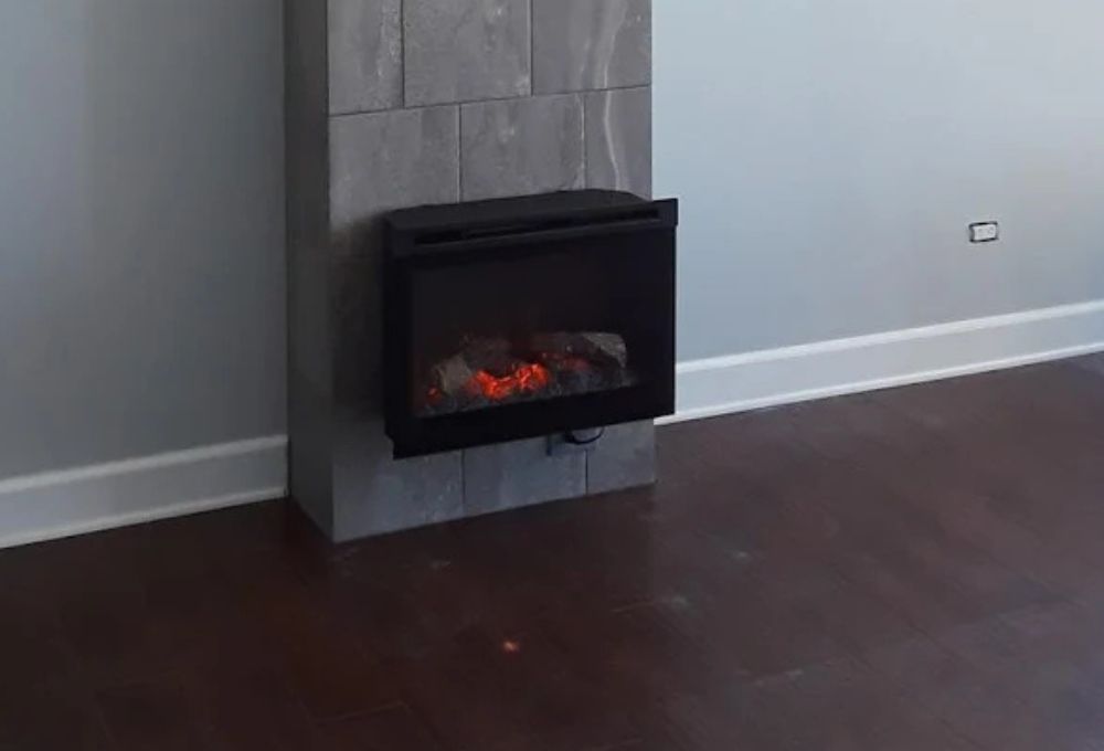 Wall-mounted black-framed fireplace insert glowing over a dark wood floor.